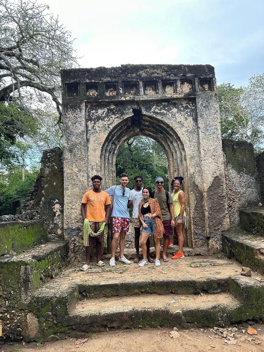 A group of visitors posing under the carved stone arch at the Gede ruins