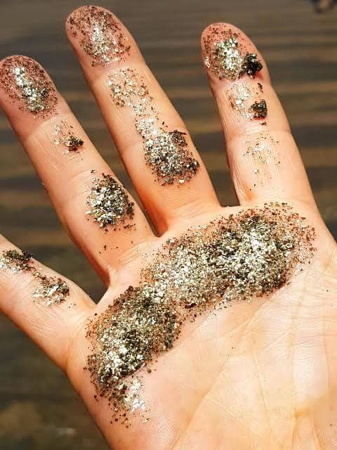 An open hand covered in glittering golden sand