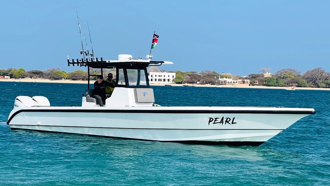 The Pearl seen side-on in the Lamu channel, rods racked on its T-top and the shore behind
