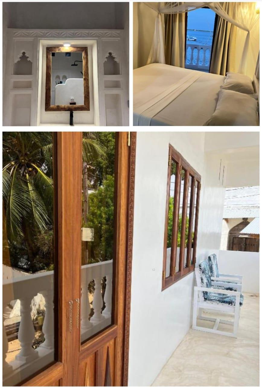A carved stone bathroom doorway, a bed looking out to the sea through an arched window, and a veranda with wooden shutters