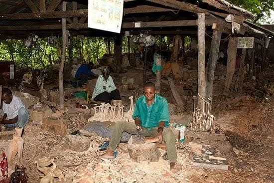 Carvers working under the timber roof of an open-sided woodcarving workshop