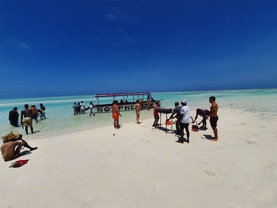 Visitors on the white sand of Sardegna 2 beside a moored excursion boat