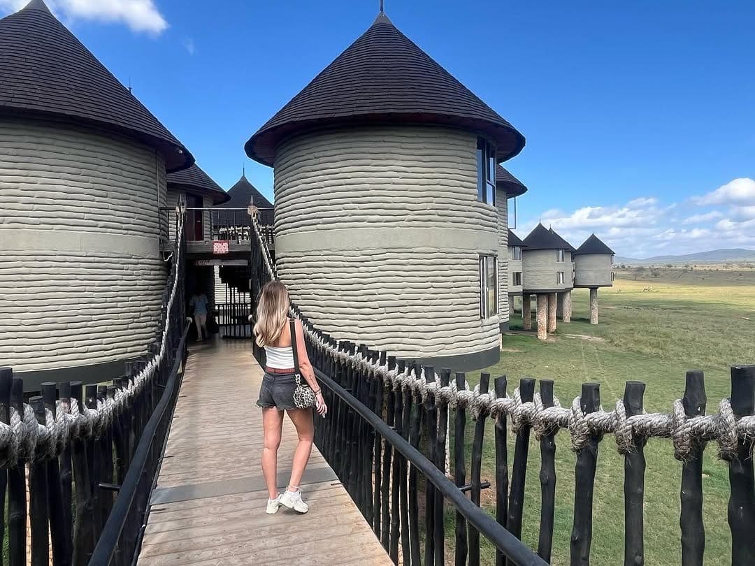 A guest crossing the raised timber walkway between the towers of Salt Lick Game Lodge