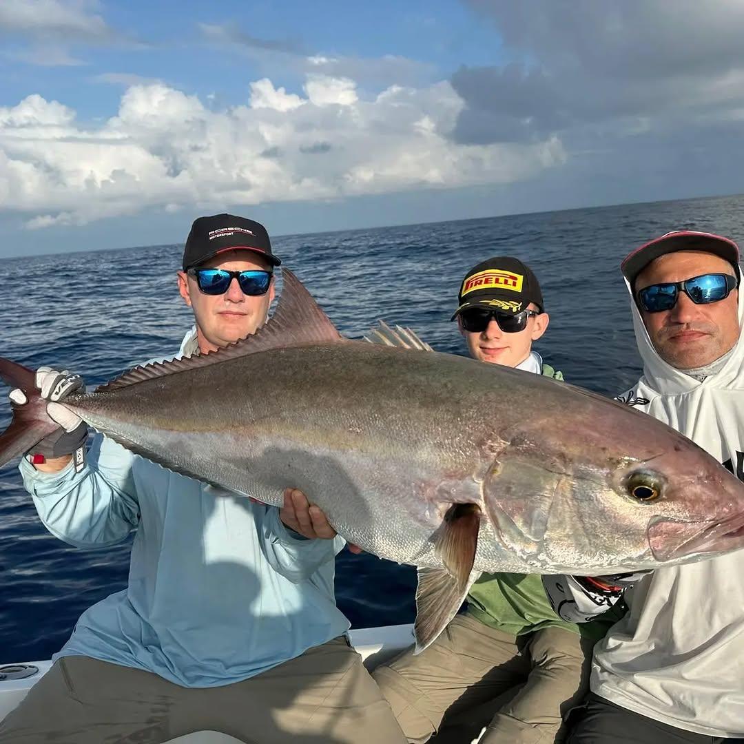 3 anglers on board holding up a large amberjack