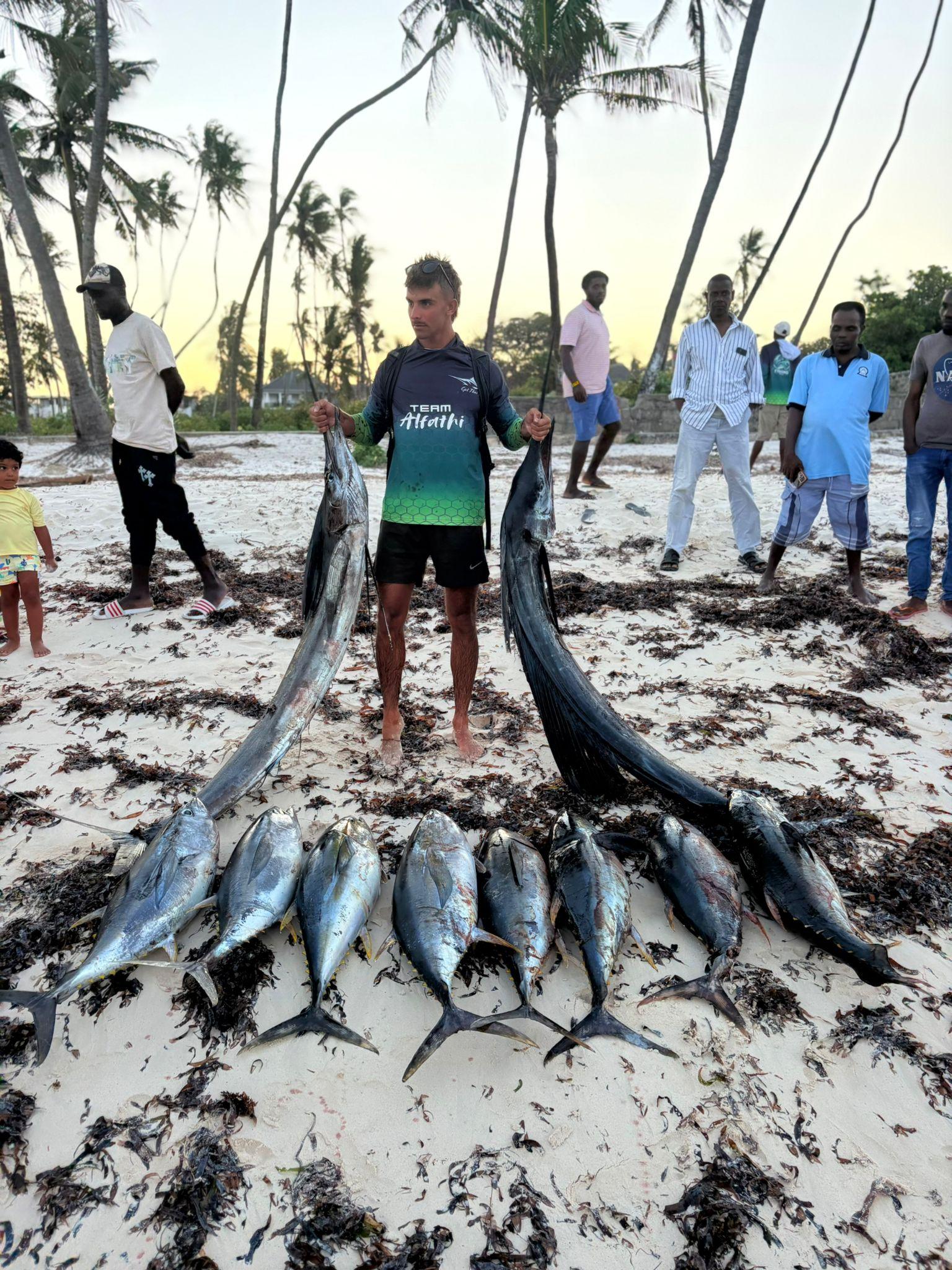 A day’s catch of tuna and 2 billfish laid out on the beach at Watamu under palm trees