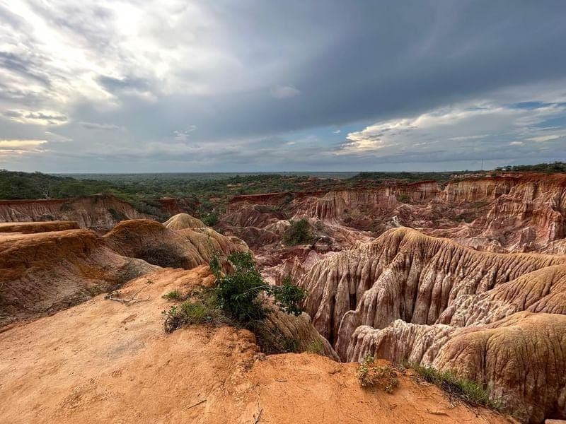 The eroded red and white gorges of Marafa seen from the rim under heavy cloud